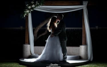 Groom kissing bride's forehead under archway silhouette