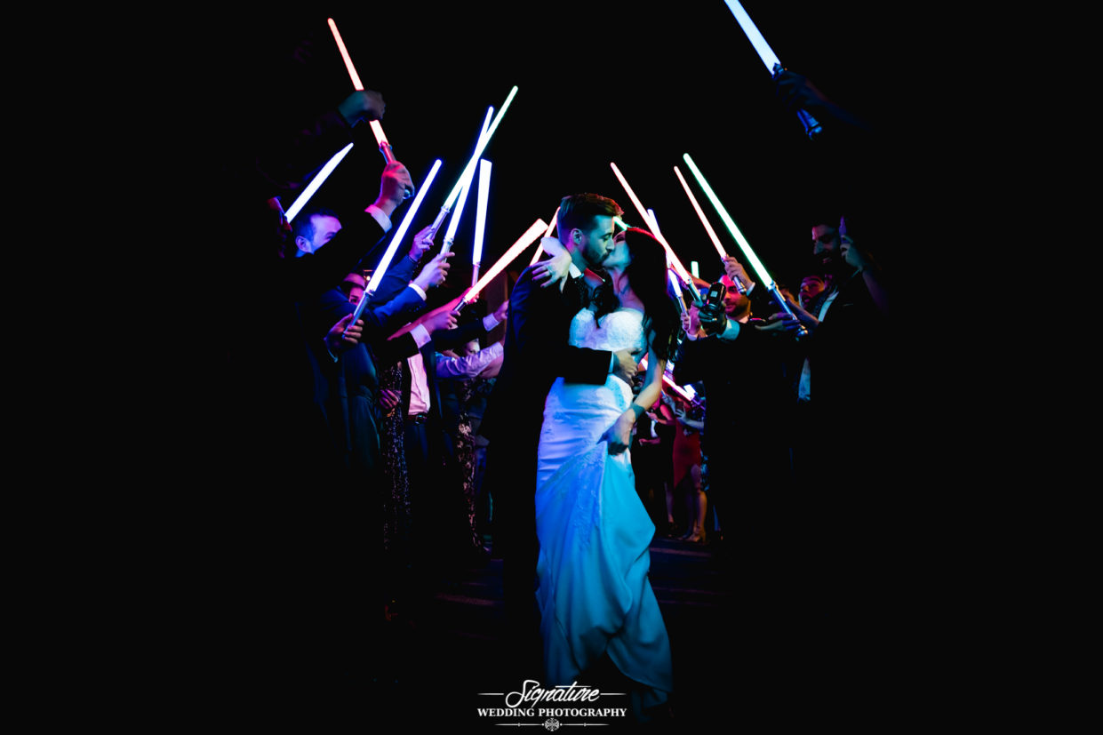 Bride and groom kissing under lightsabers