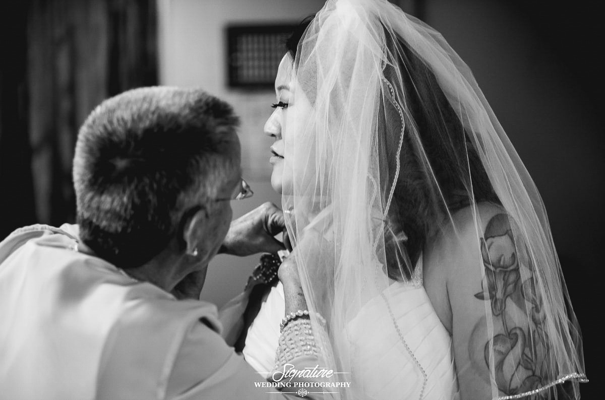 Bride getting jewelry put on black and white