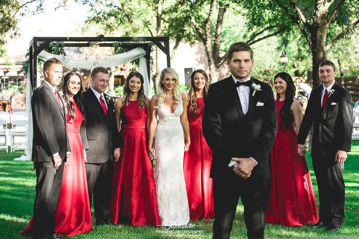 Bride standing with wedding party behind groom for first look