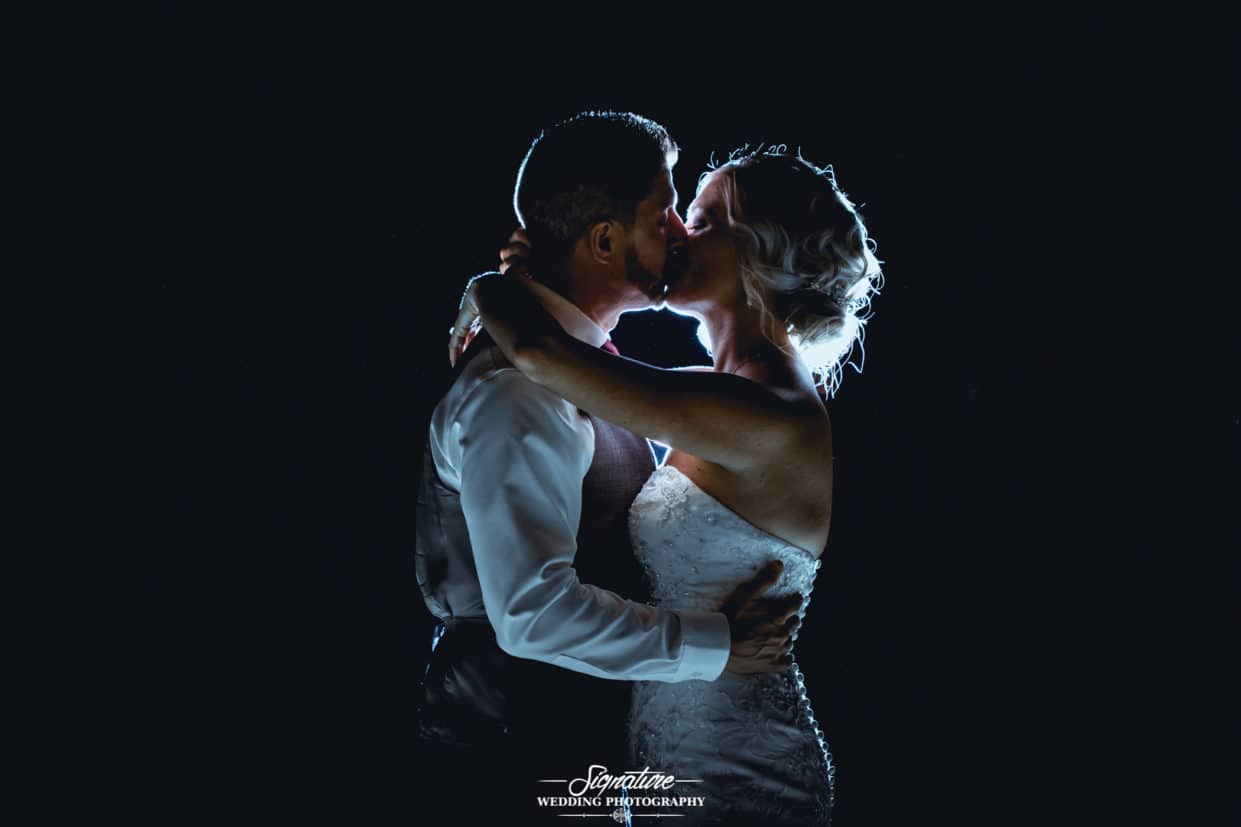 Bride and groom kissing backlit silhouette