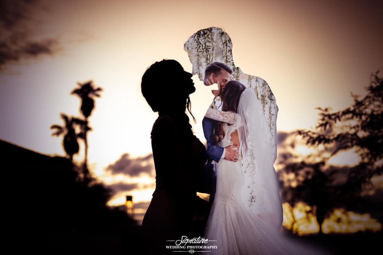 Silhouette bride and groom at sunset with bride and groom kissing
