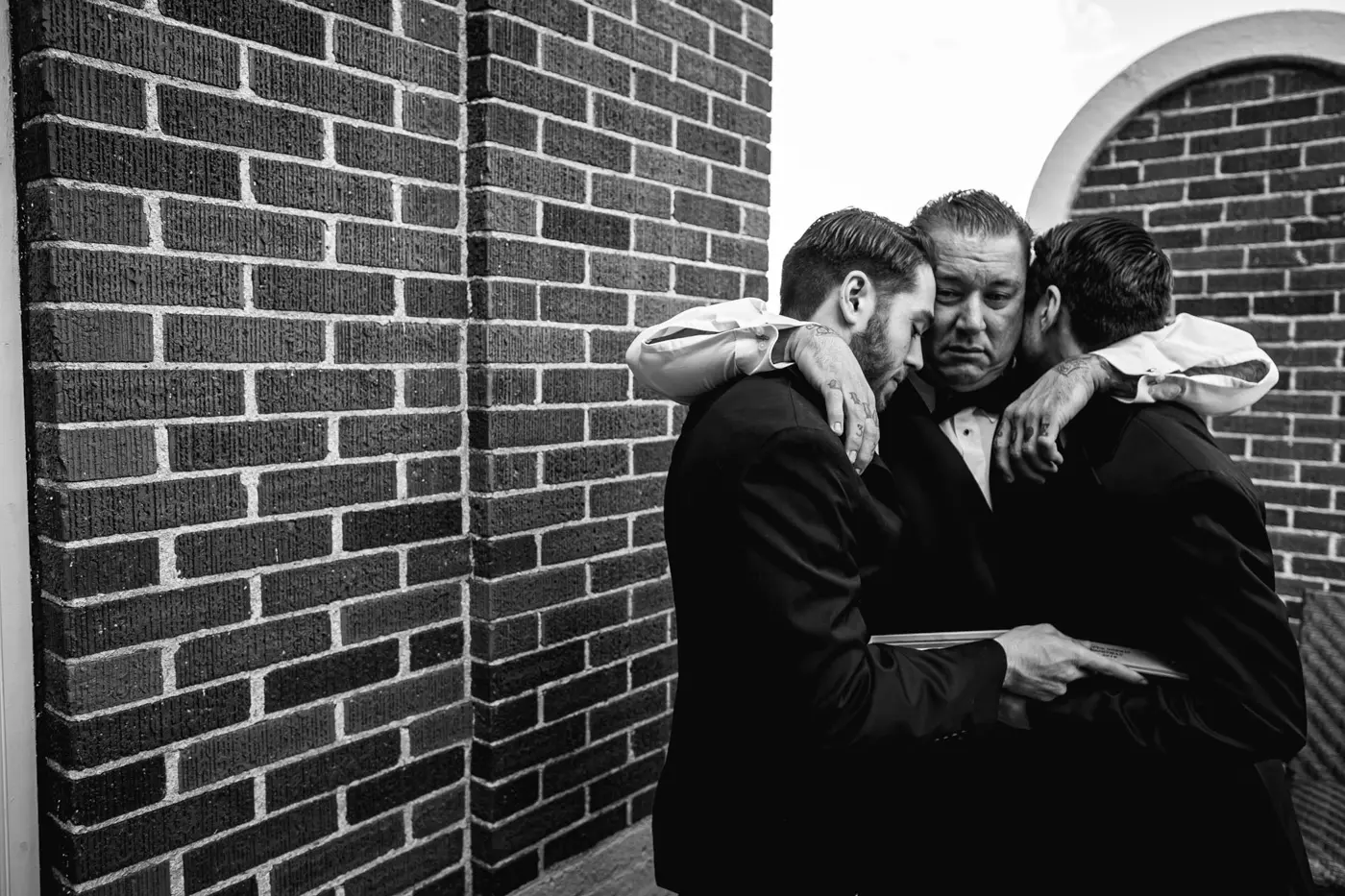 Groom with arms around groomsmen black and white