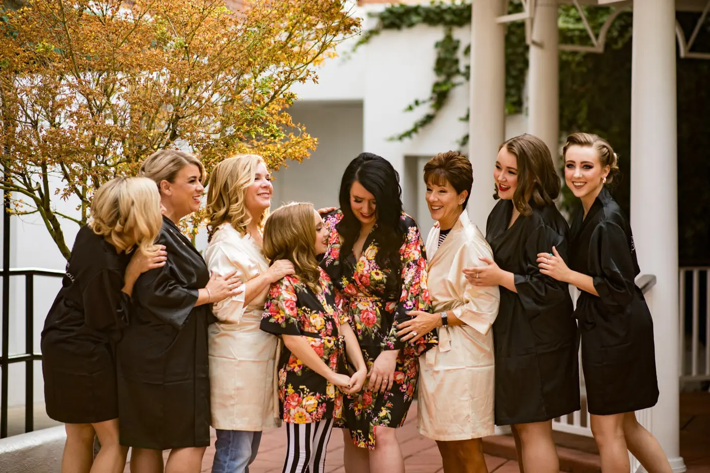 Bride, flower girl, matriarchs, and bridesmaids smiling together in robes