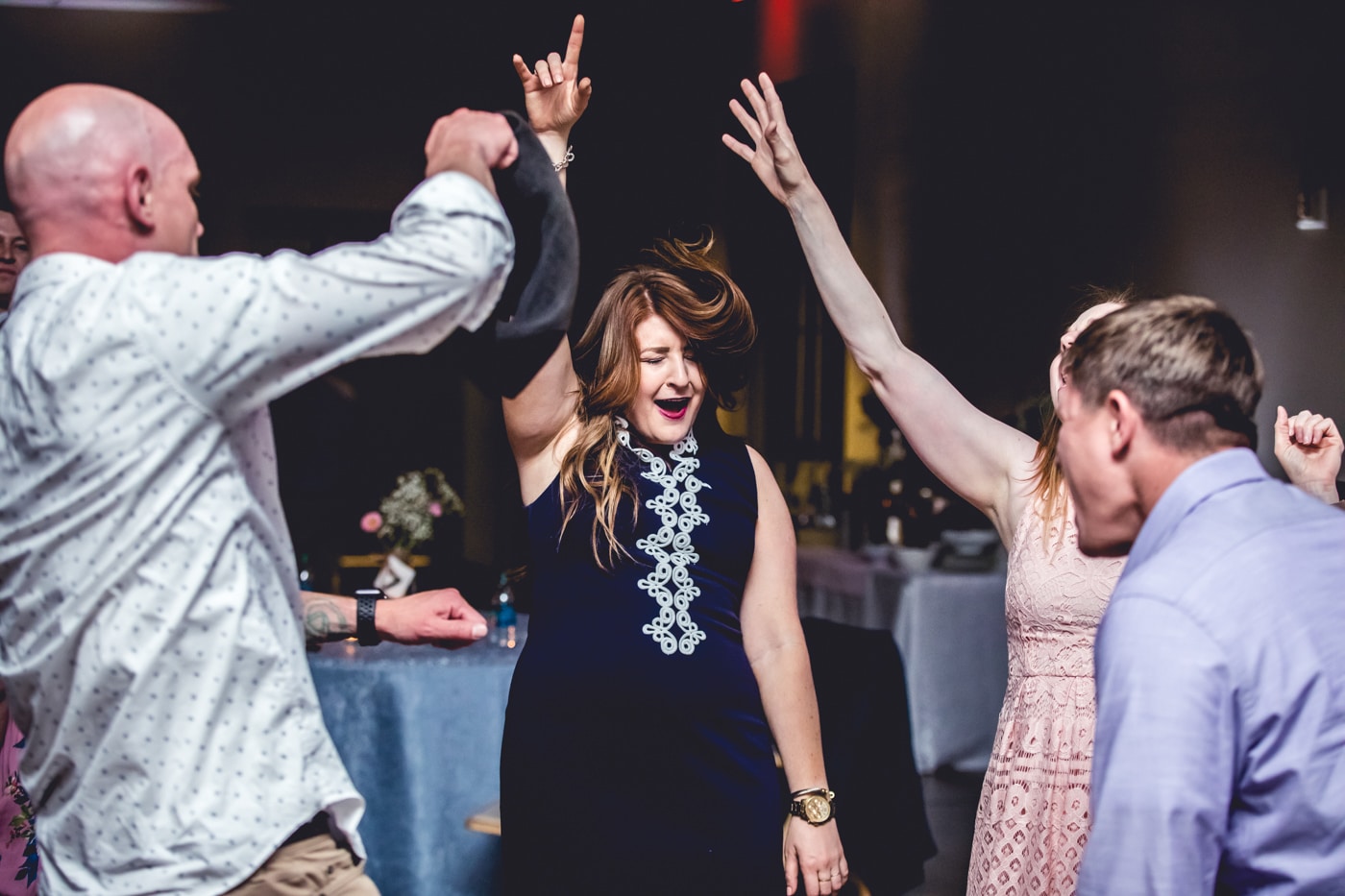Wedding guests dancing with arms up at reception