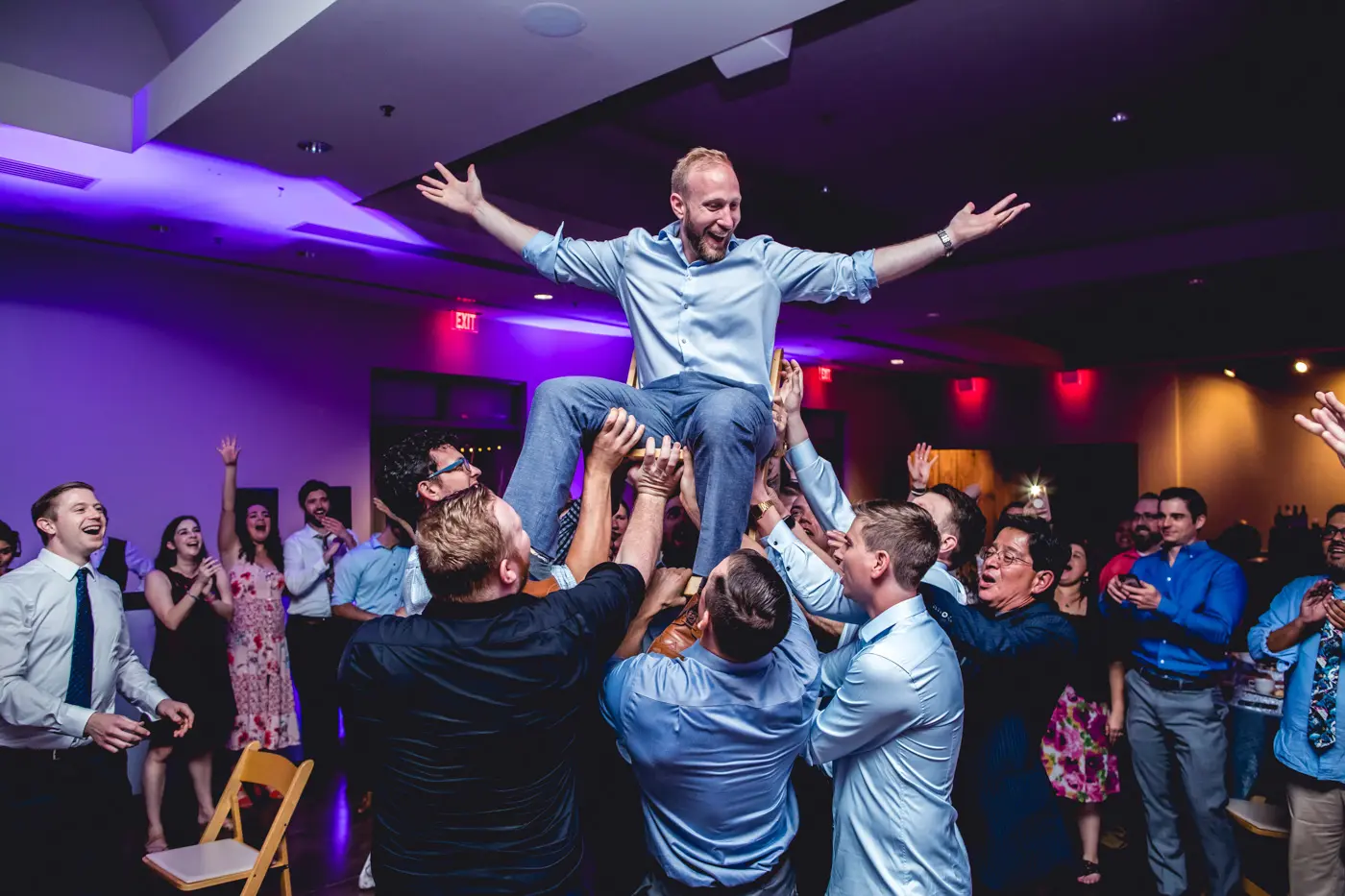 Groomsmen lifting up groom on chair