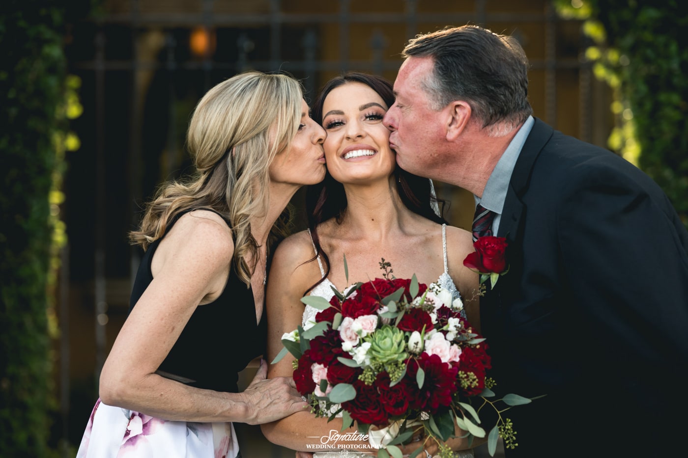 Mother and father kissing bride on cheek
