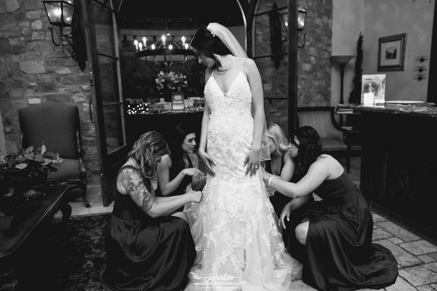 Bridesmaids knelt helping with wedding dress