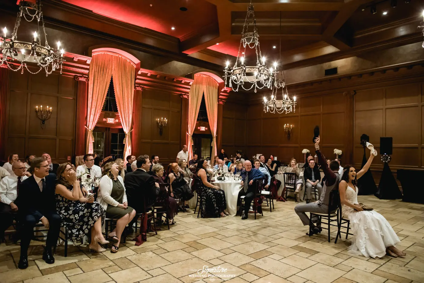 Bride and groom sitting on chairs back to back on dance floor