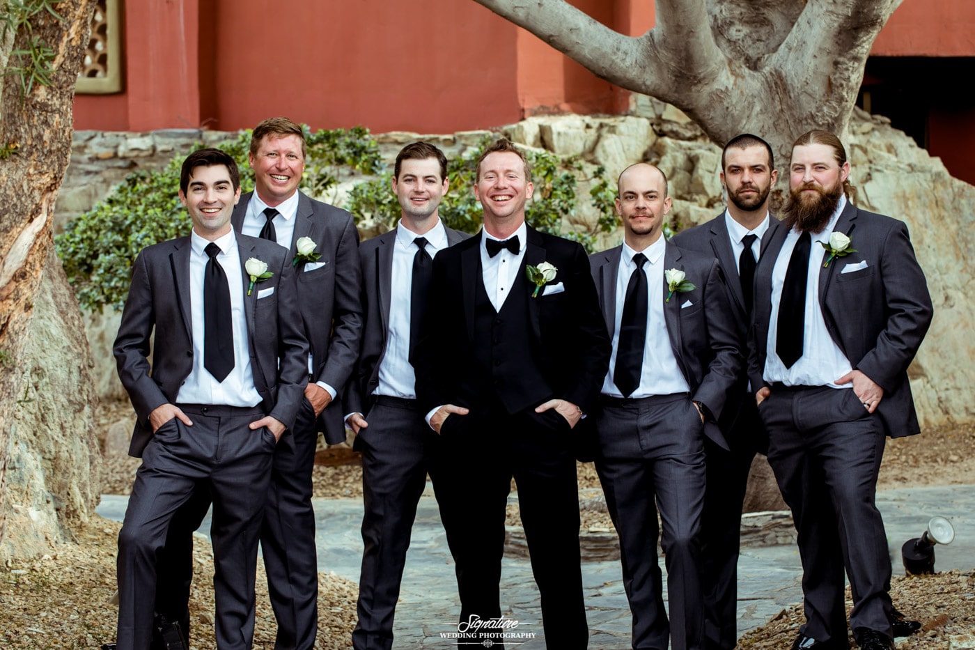 Groom and groomsmen smiling at camera outside
