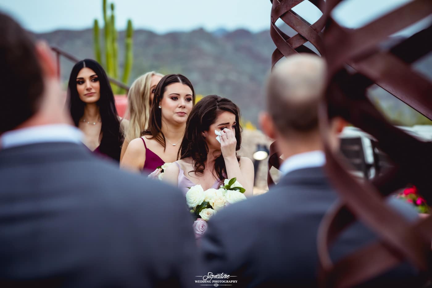 Bridesmaid wiping tear at ceremony candid