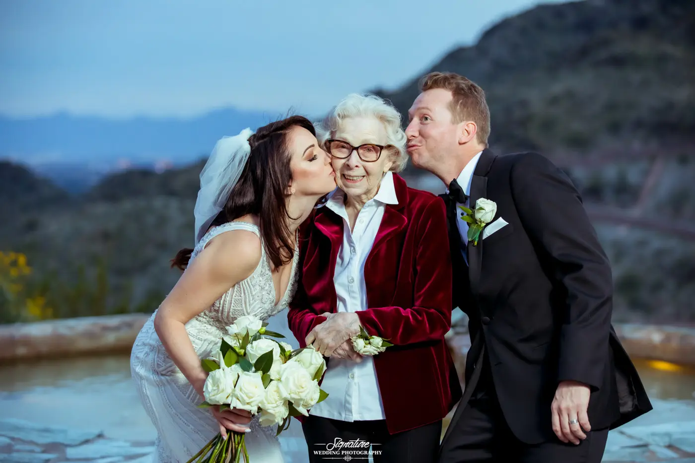 Bride and groom kiss matriarch on cheek