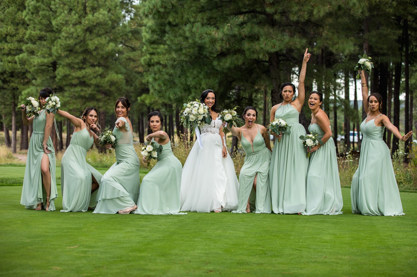 Bride and bridesmaids fun pose in front of trees