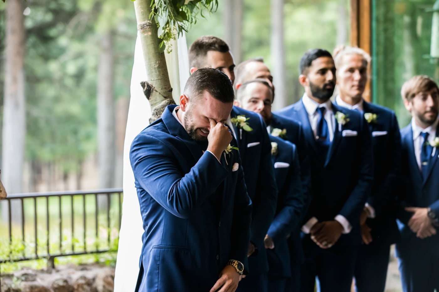 Groom emotional standing with groomsmen at ceremony