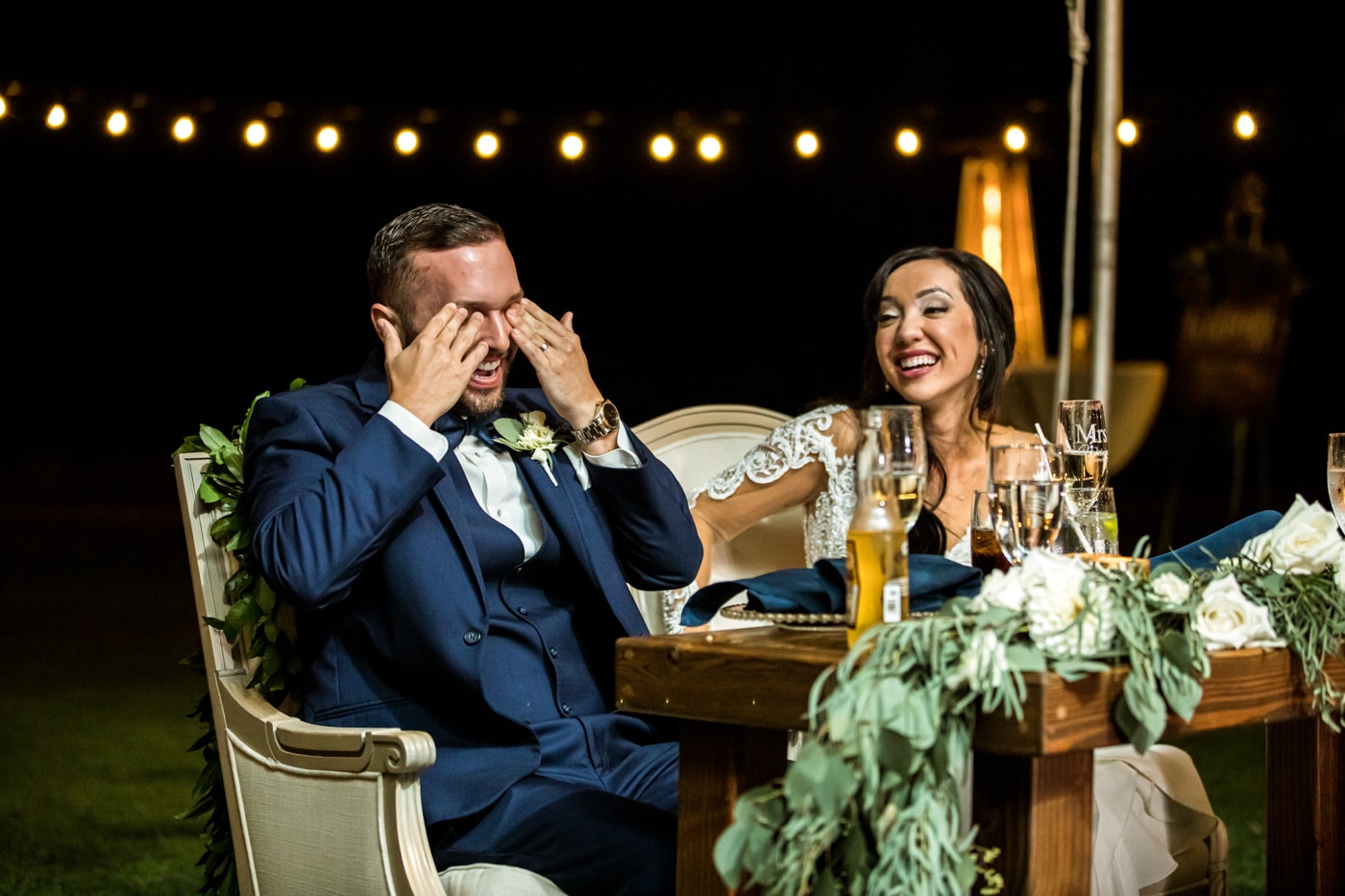 Bride and groom laughing at sweetheart table