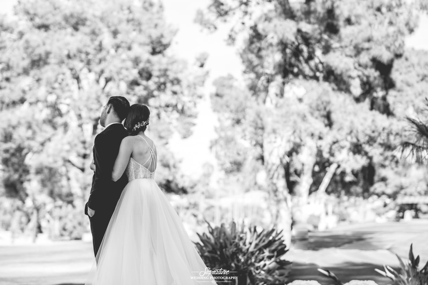 Bride hugging groom from behind black and white