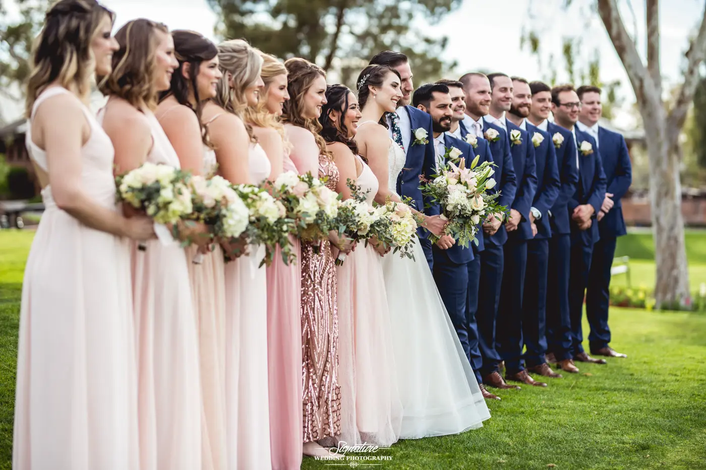 Bride and groom posing with wedding party side shot