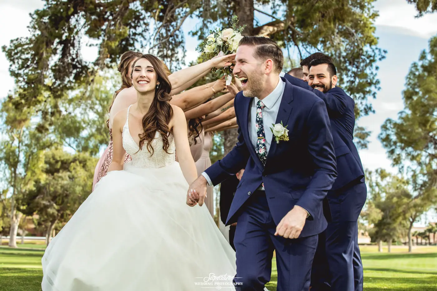 Bride and groom walking under arm tunnel