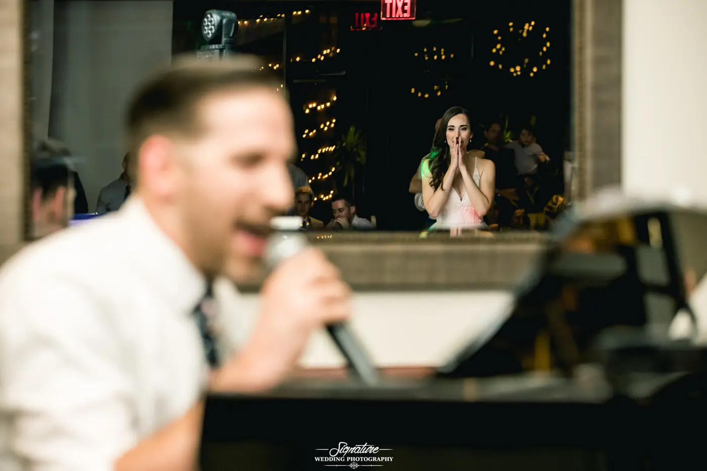 Bride watching man at piano with mic