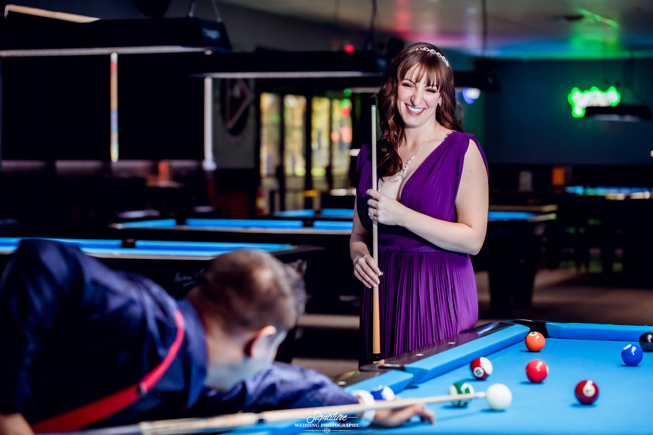 Woman smiling at man playing billiards