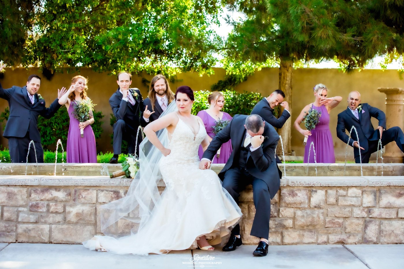 Bride and groom with wedding party funny pose with fountain