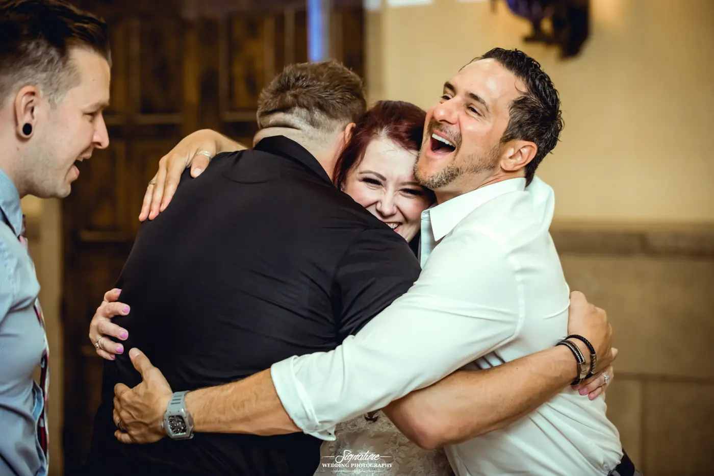 Bride and groom hug wedding guest