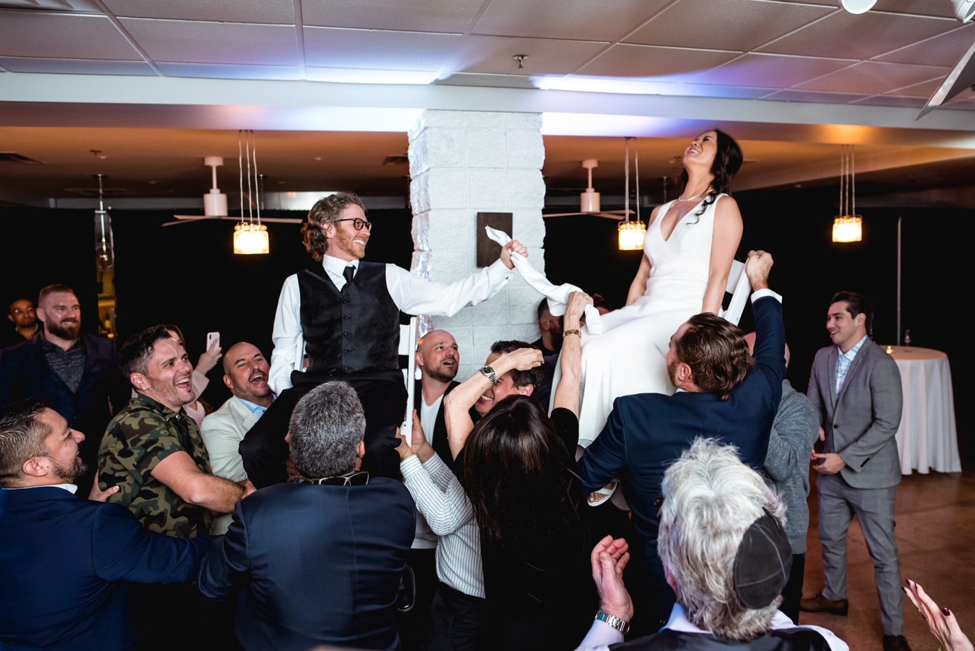 Bride and groom on lifted chairs for horah tradition
