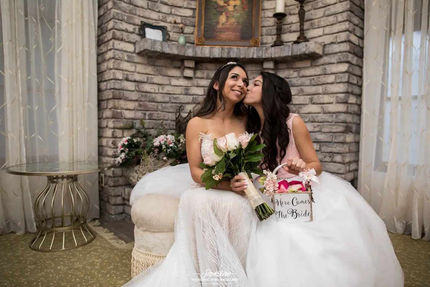 Flower girl kissing bride on cheek sitting down