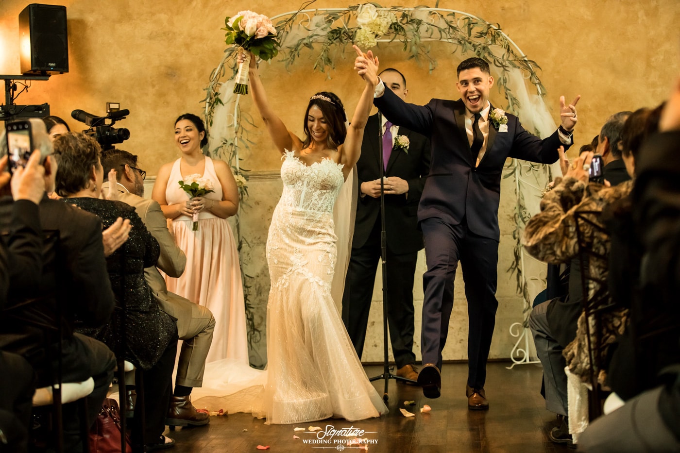 Bride and grooms with arms up after ceremony
