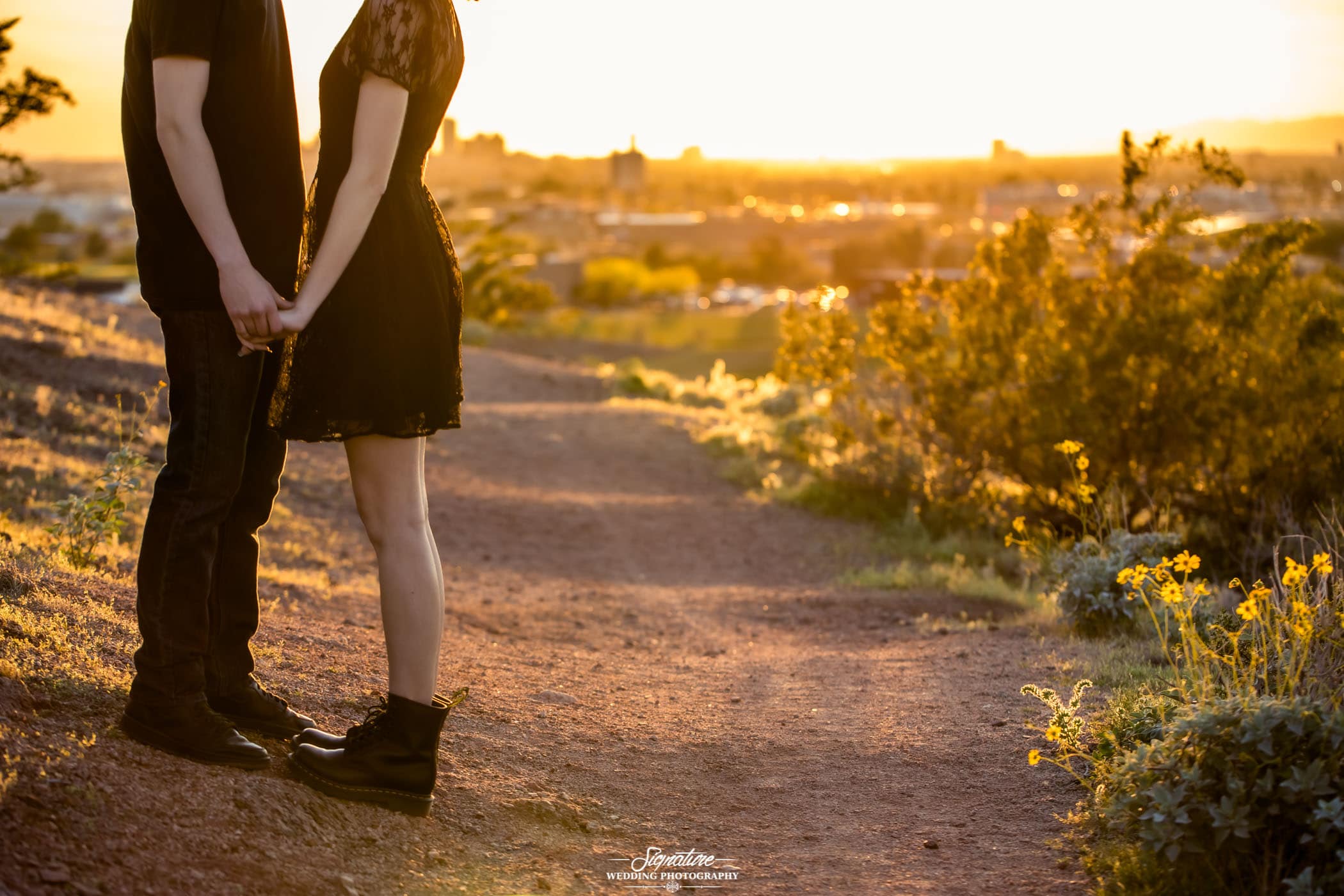 Couple feet facing each other holding hands on desert pat