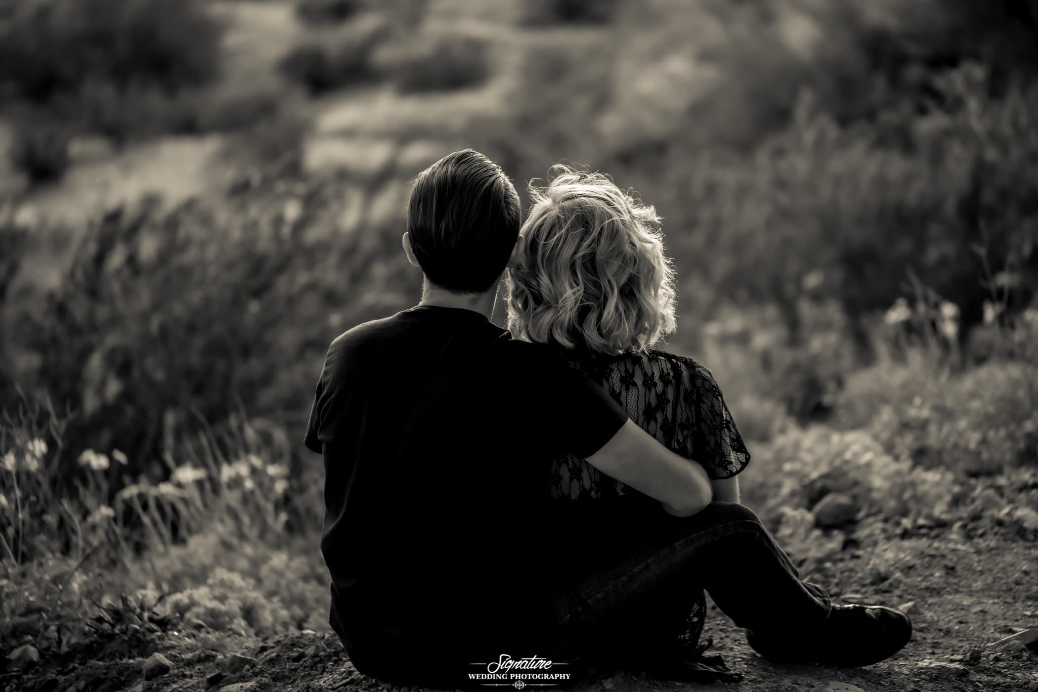 Behind shot of couple sitting together in desert black and white