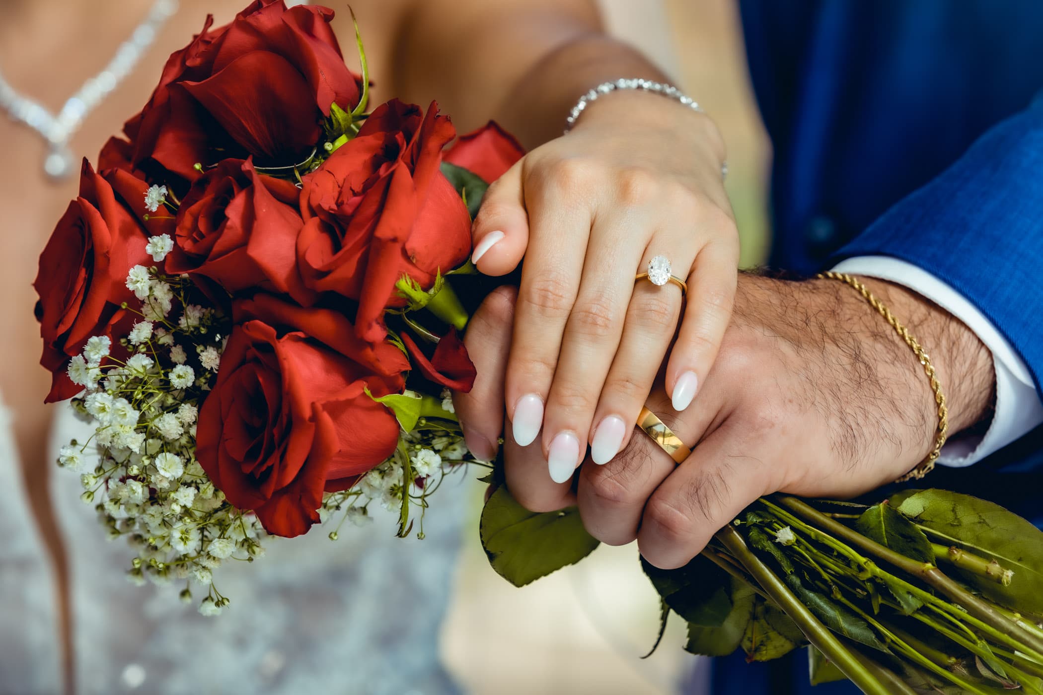 Wedding rings on hands close up holding bouquet