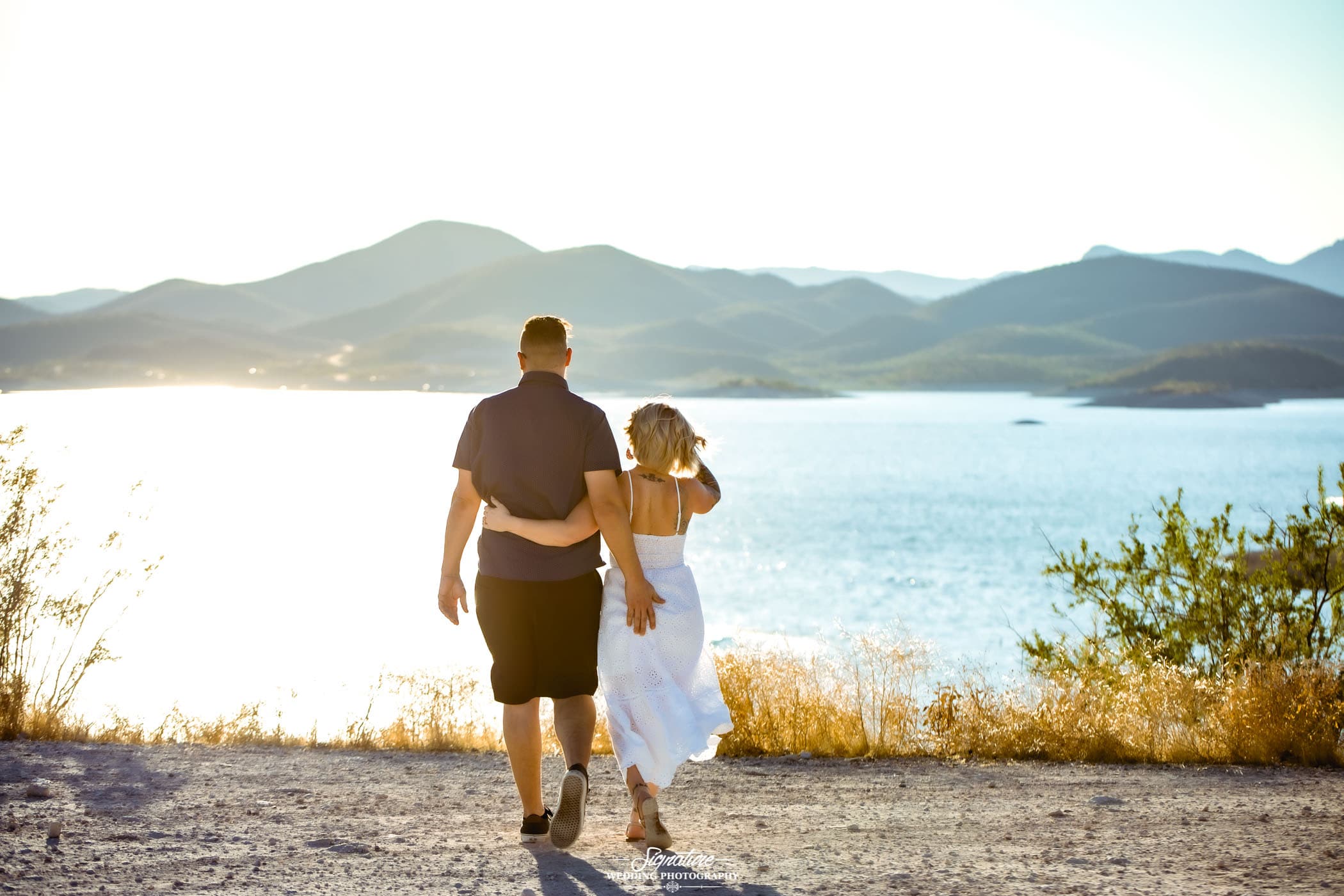 Couple walking toward lake with arms around each other