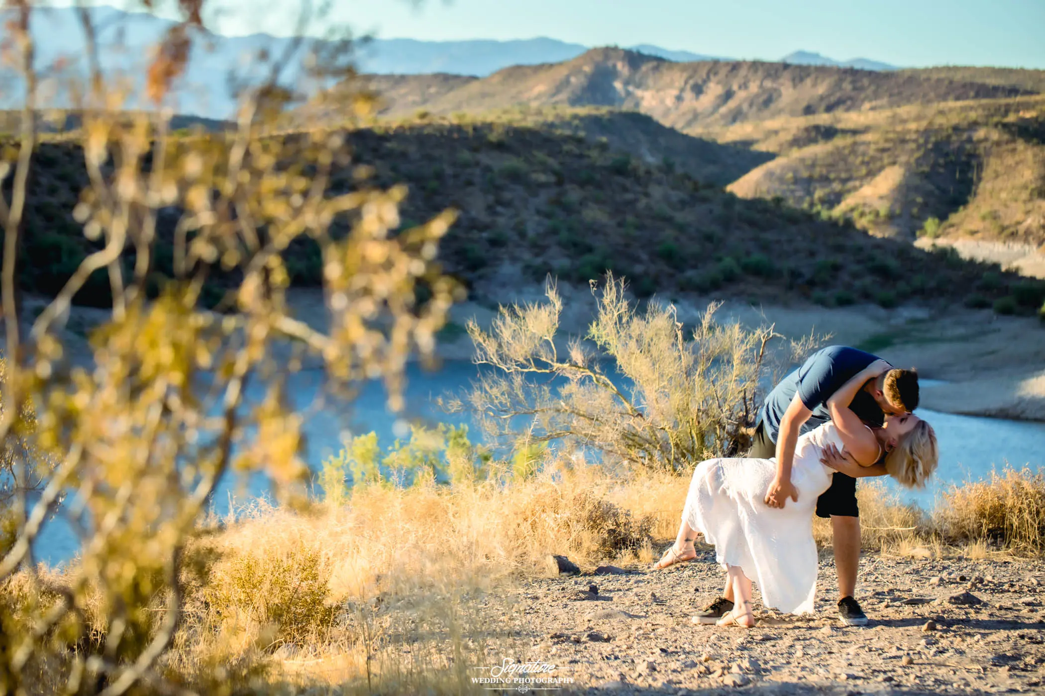 Couple dipping and kissing at lake in desert