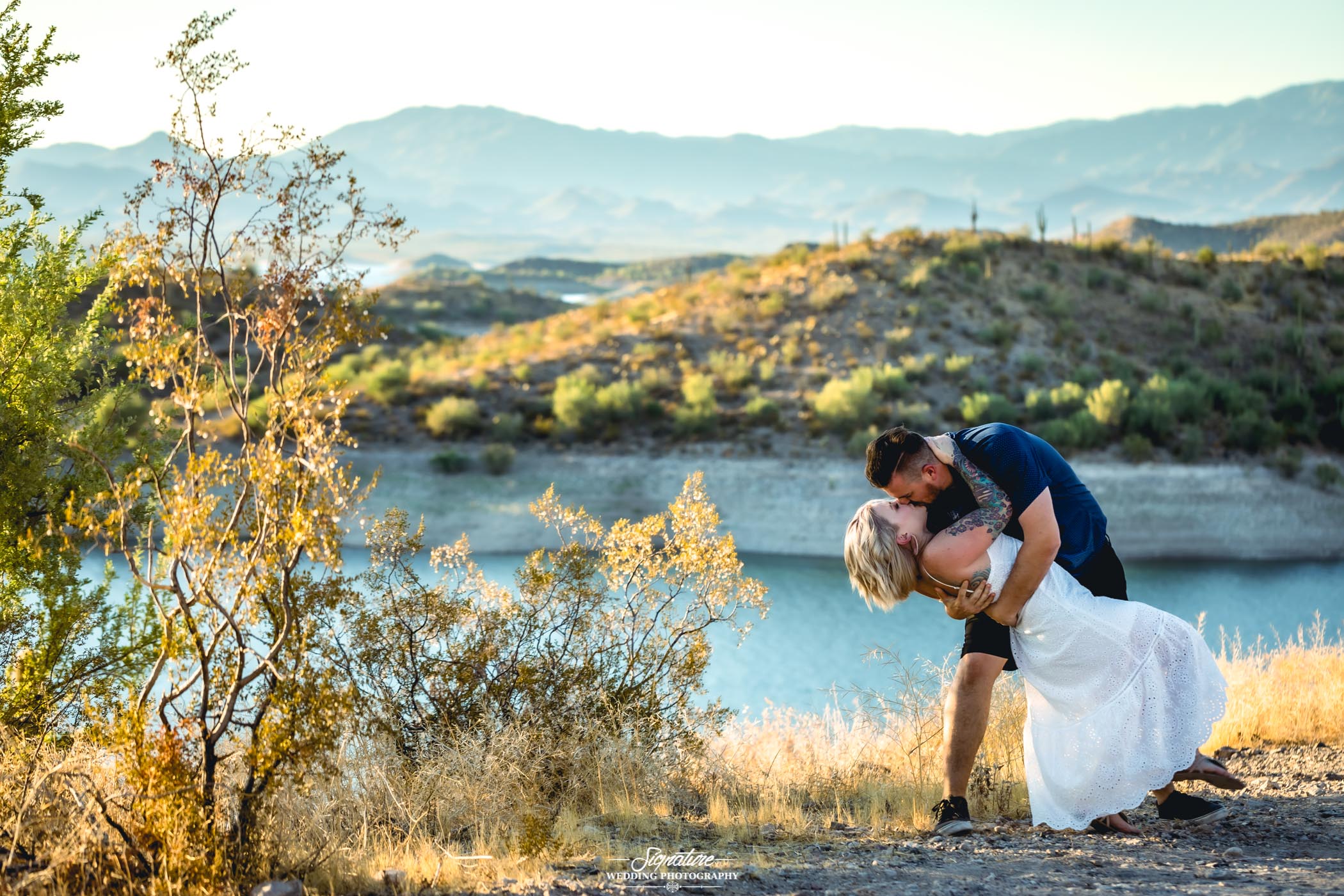 Couple dipping and kissing at lake in desert