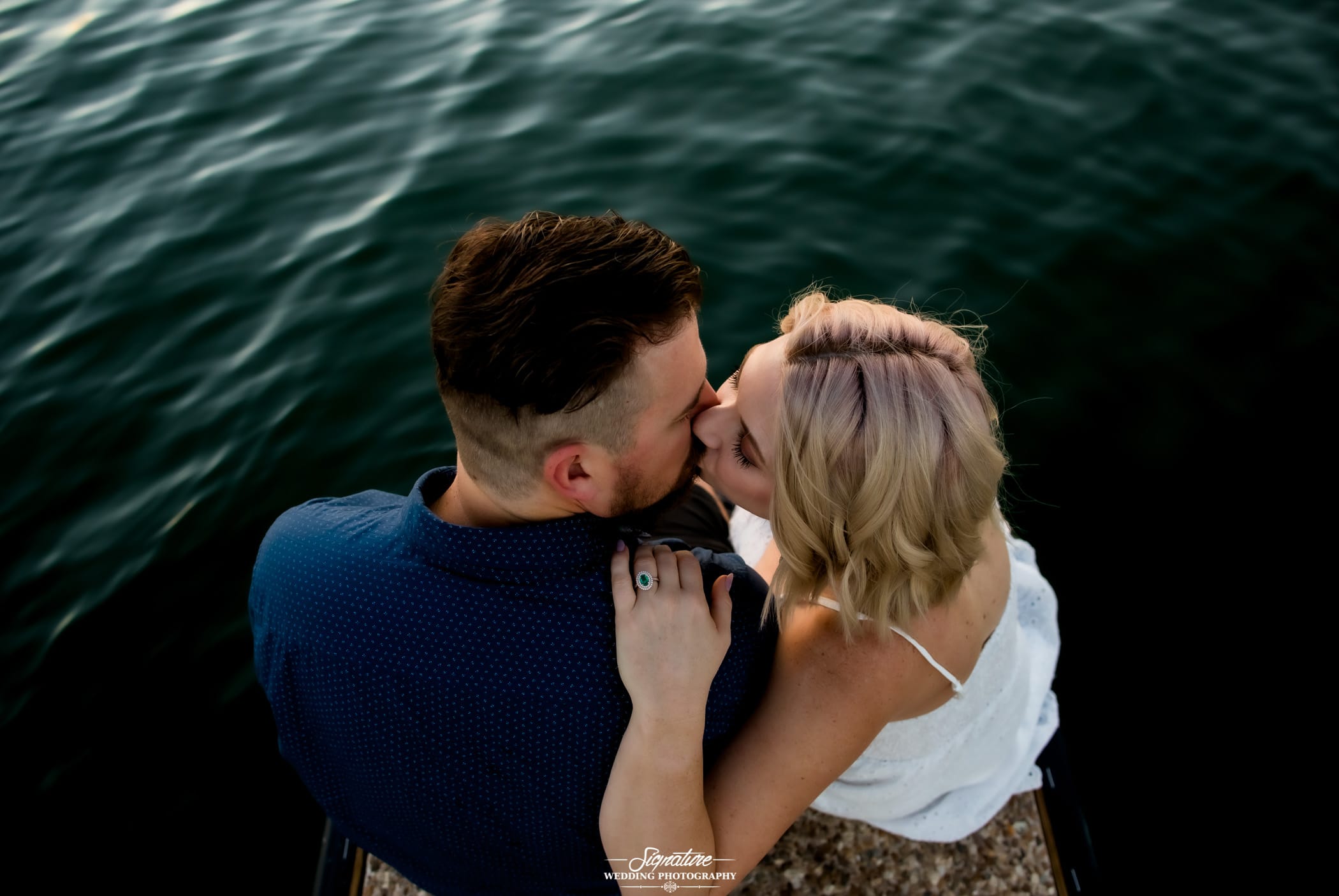Couple kissing sitting in front of lake