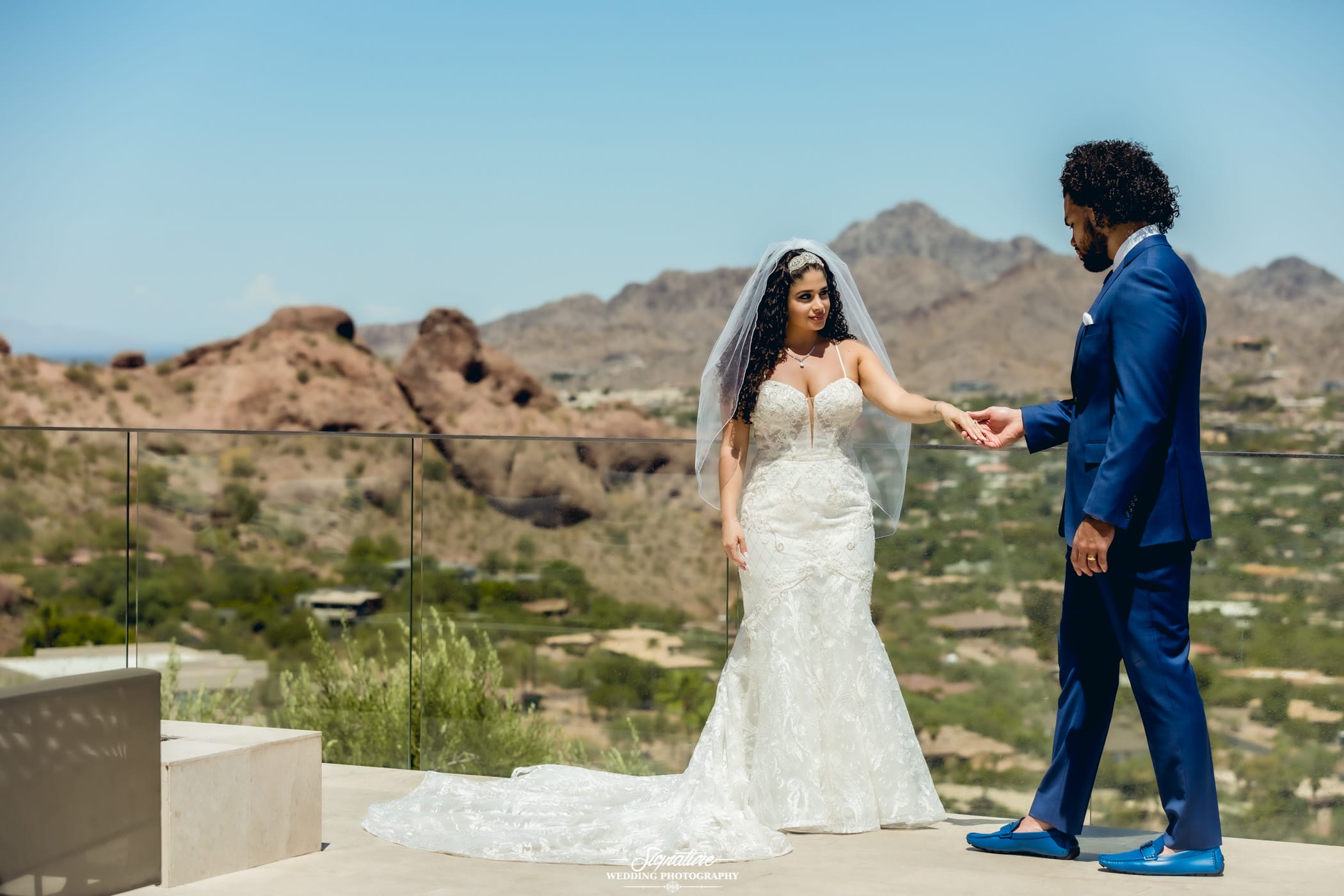 Bride and groom holding hands on balcony in desert