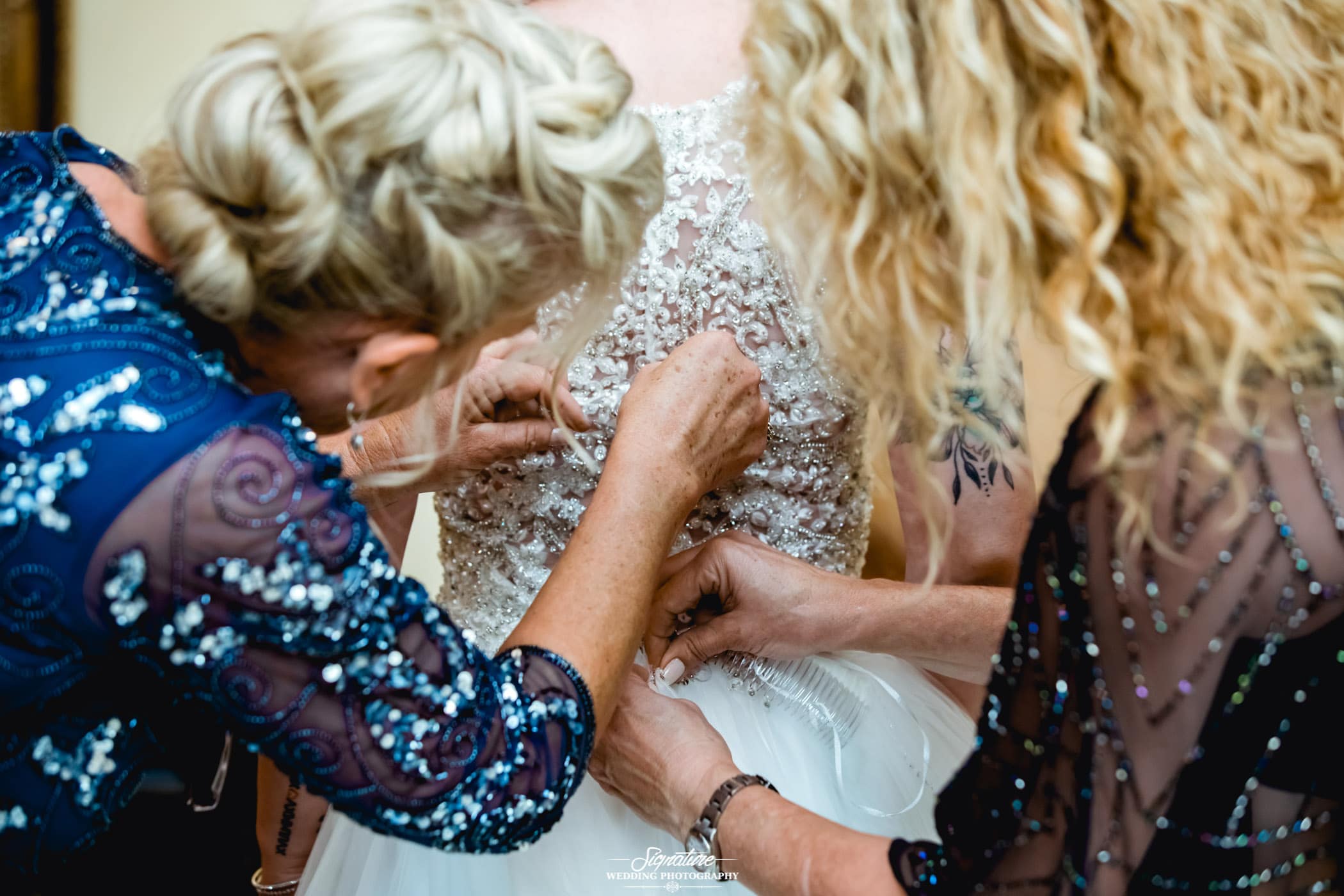 Matriarchs adjusting back of brides dress