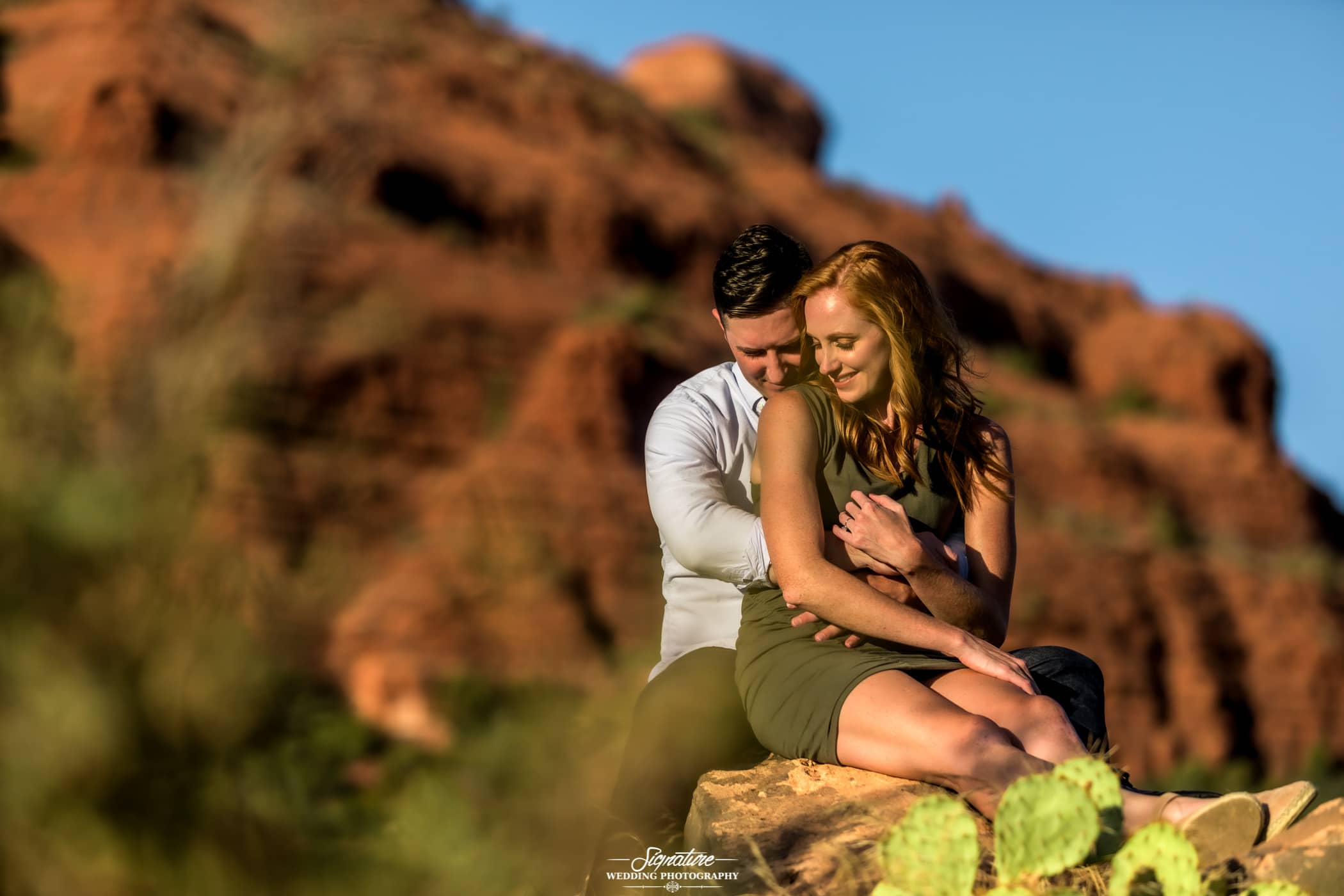 Couple sitting hugging in front of desert mountain