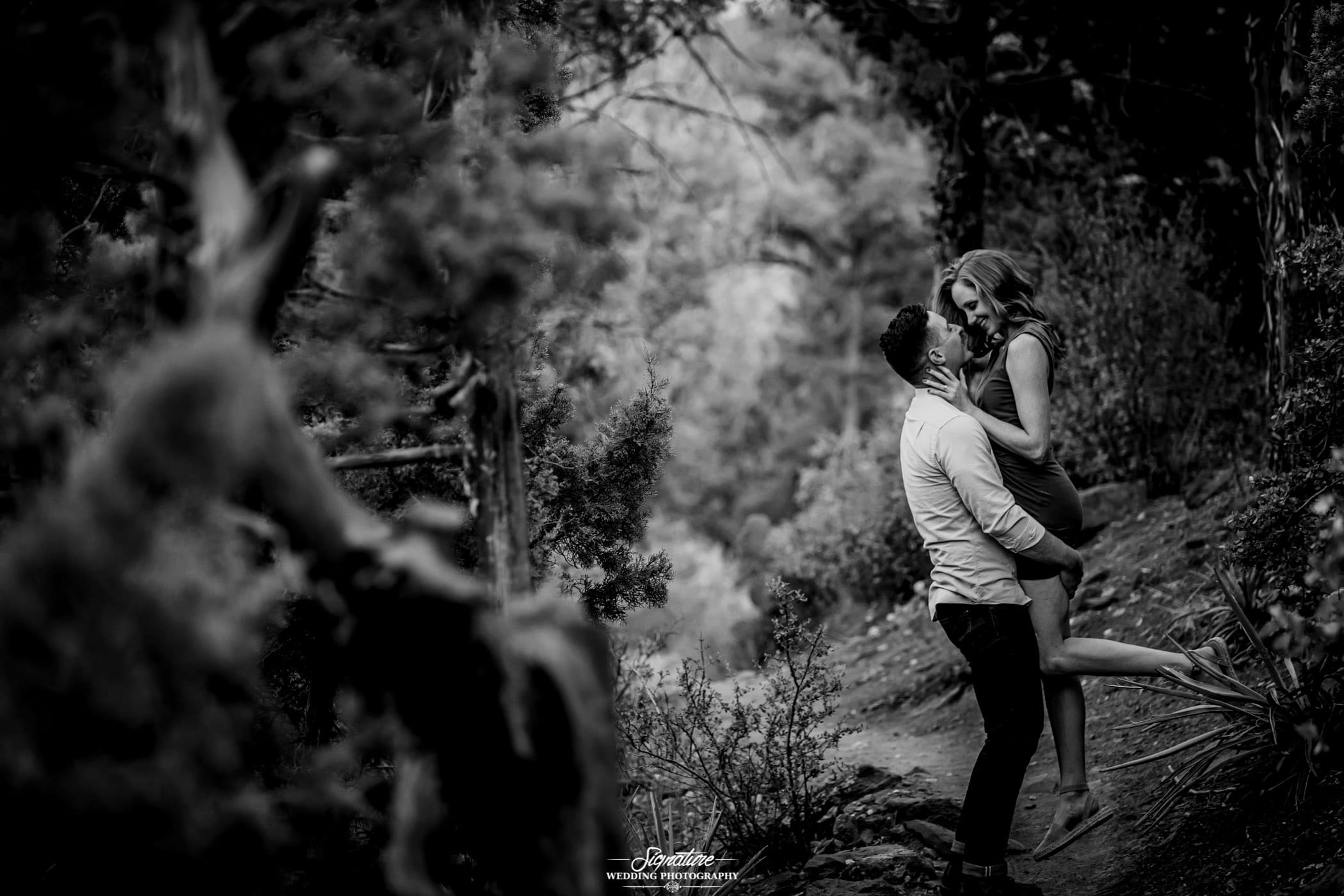 Man picking up woman smiling at each other in forest black and white