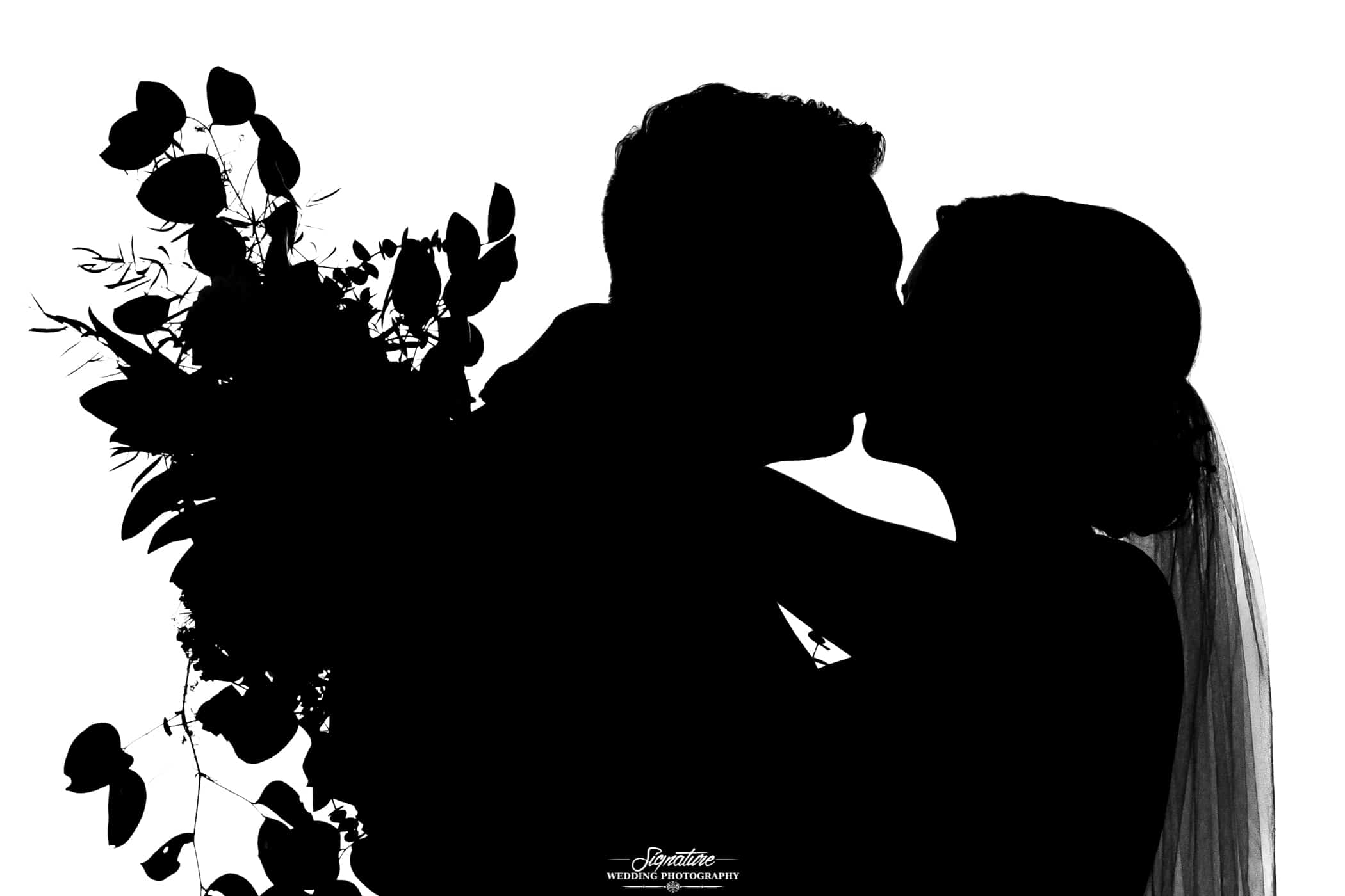 Bride and groom kissing with bouquet silhouette