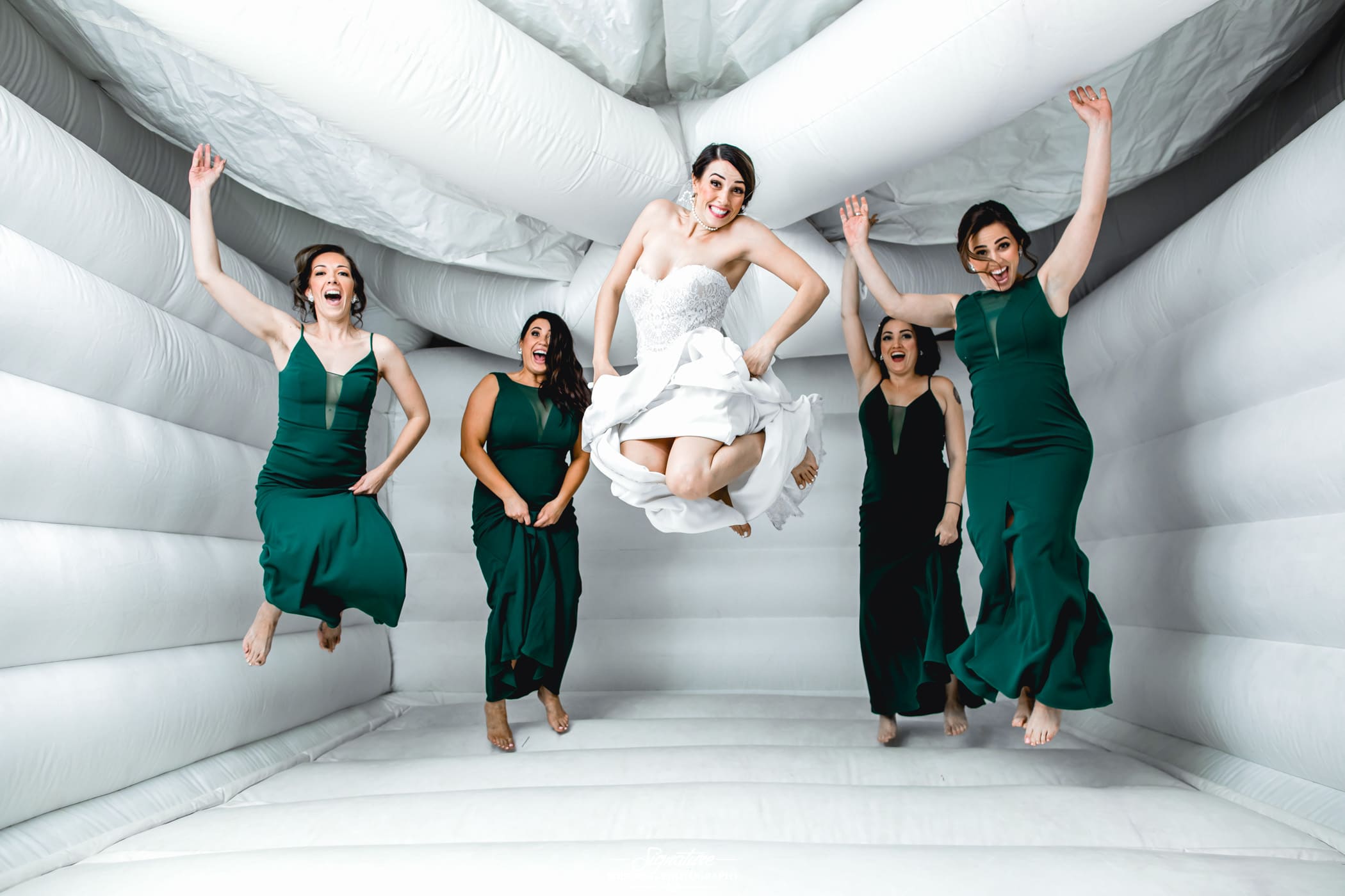Bride with bridesmaids jumping in bounce house