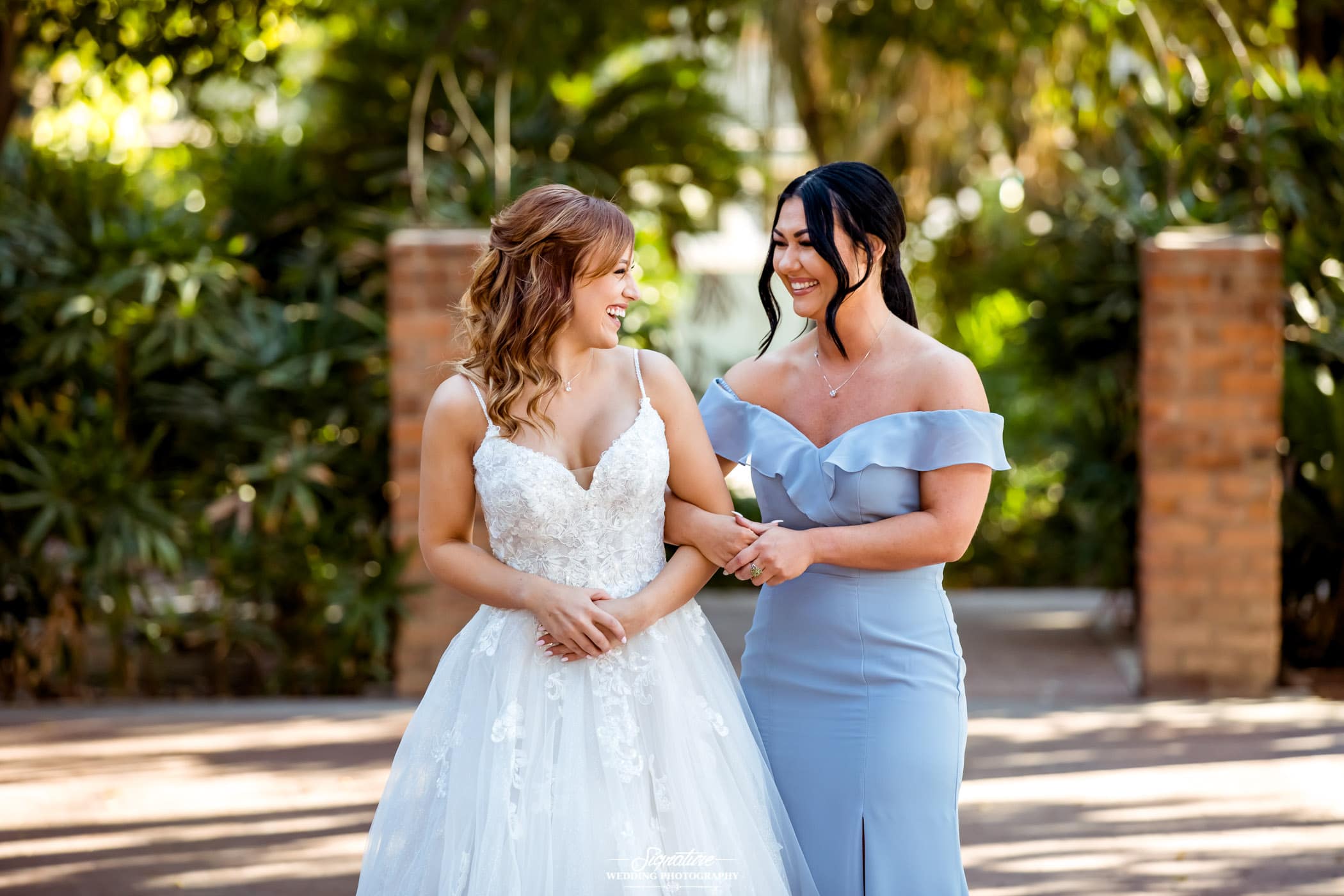 Bride and maid of honor smiling at each other