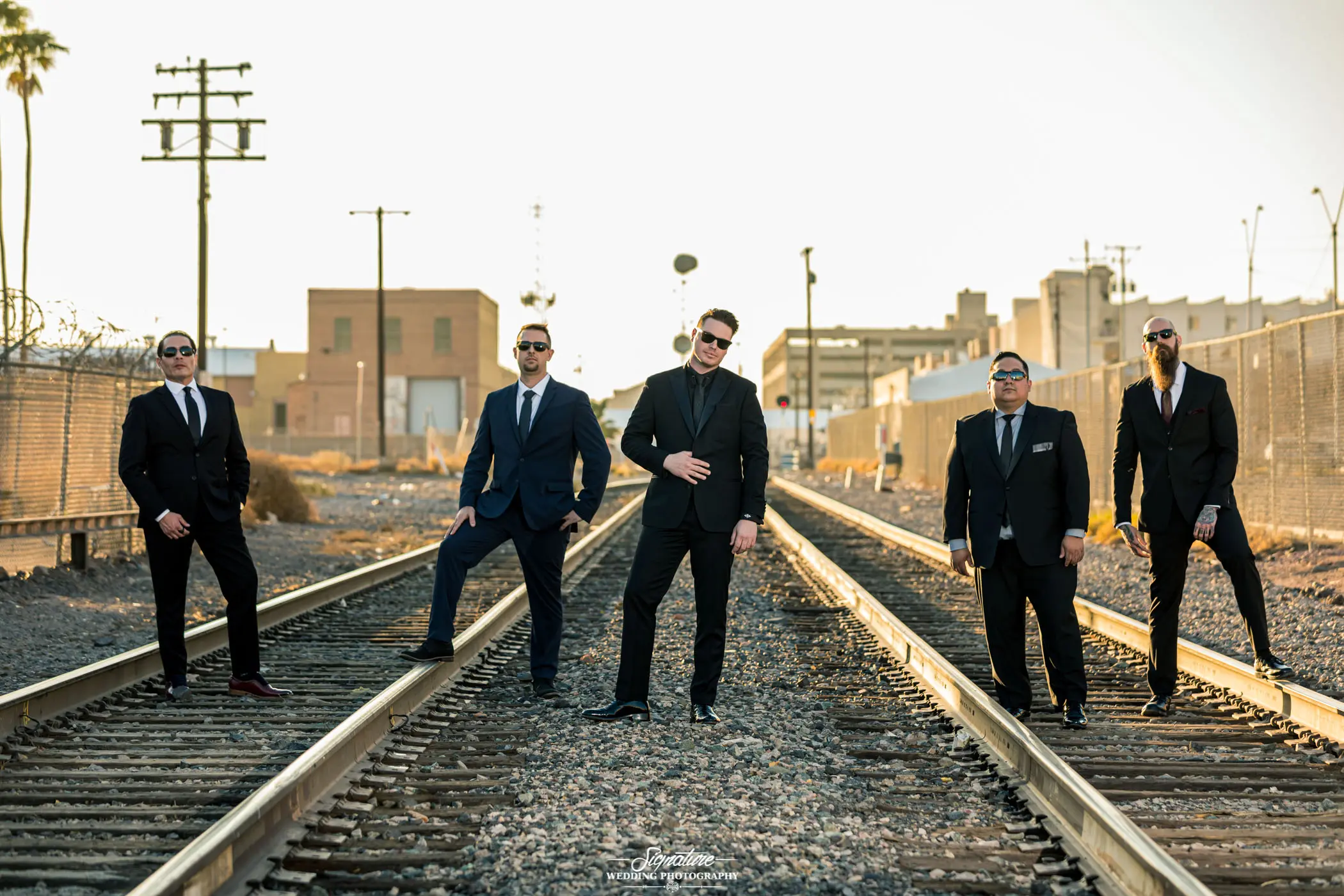 Groom and groomsmen on train tracks