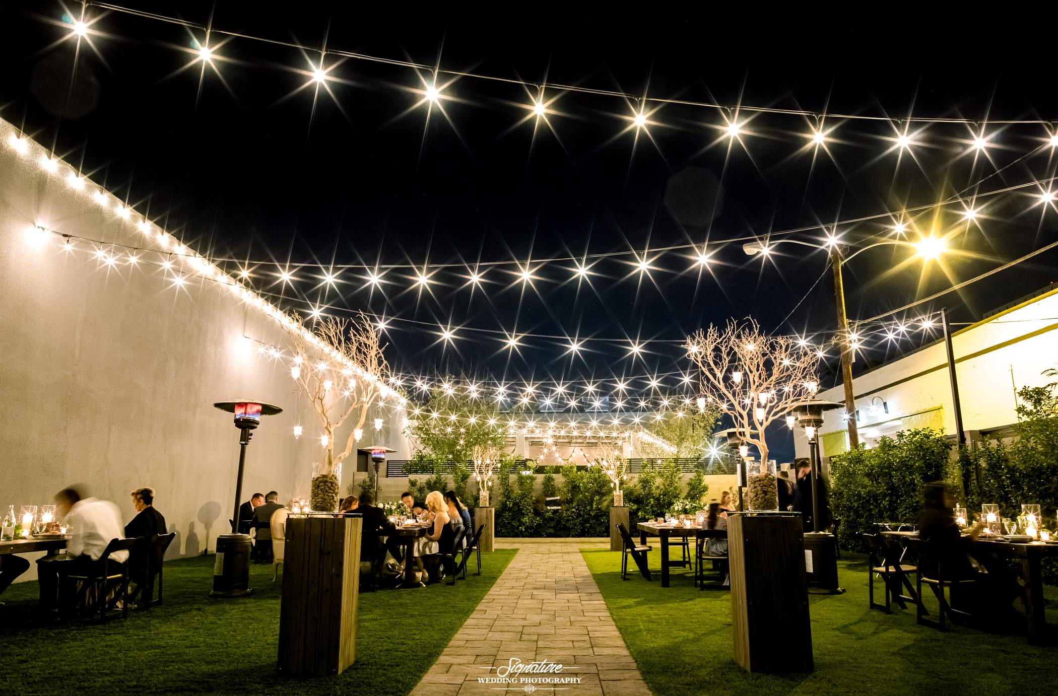 Wedding reception tables set up under string of lights