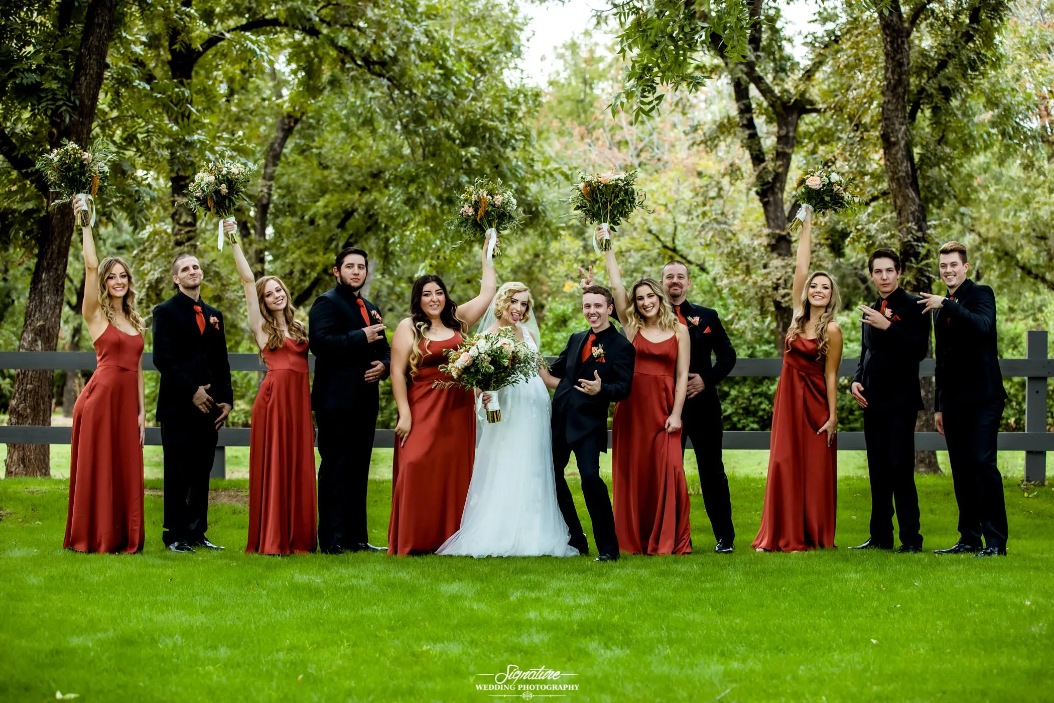 Bride and groom with wedding party fun pose outside