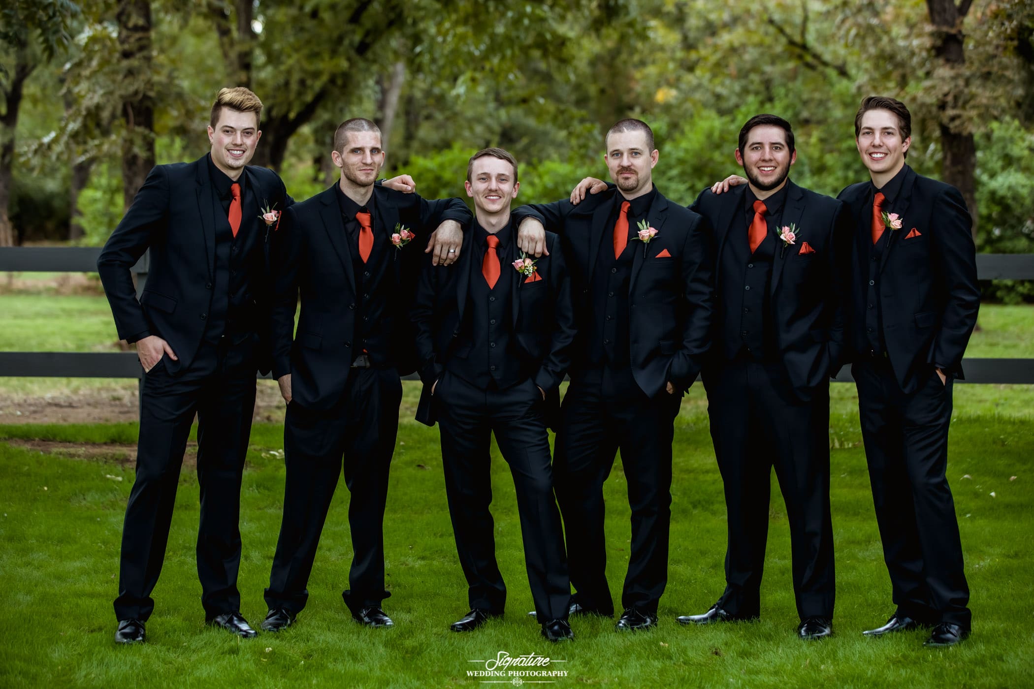 Groom and groomsmen with arms on shoulders outside
