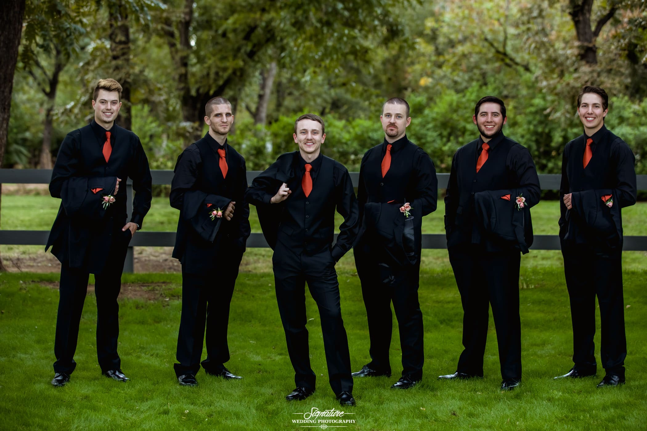 Groom and groomsmen holding jackets outside
