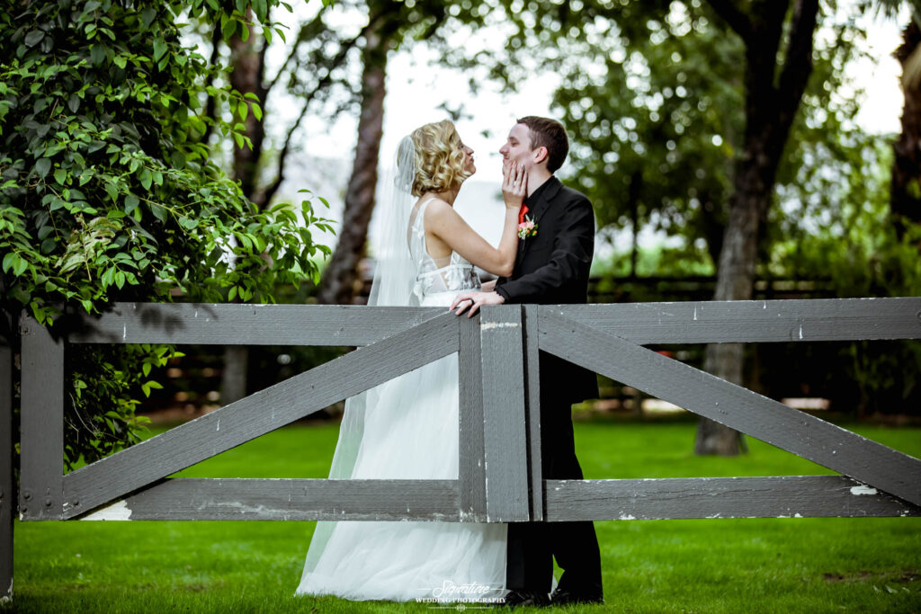 Bride and groom funny pose behind wooden gate