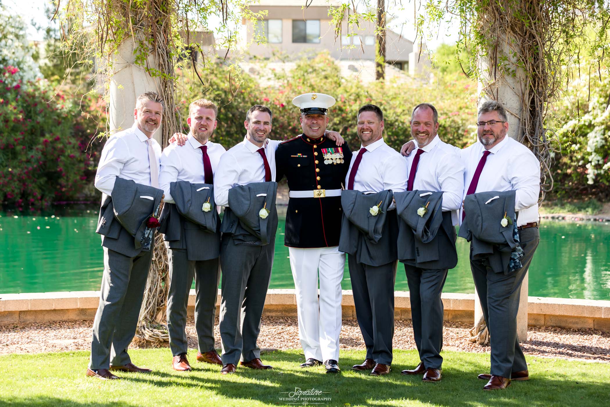 Groom with groomsmen in front of water outside